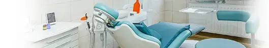 A modern dental office at Dent VIP in Chișinău featuring a teal dental chair, equipment, and a clean, white interior design