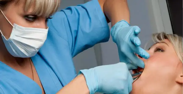 Dentist in Chișinău, Moldova performing a tooth extraction procedure using surgical tools